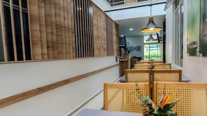 A modern interior with a long reception desk, wooden paneling, and a seating area with rattan chairs. - Hotel Alcaravan (Medellin)