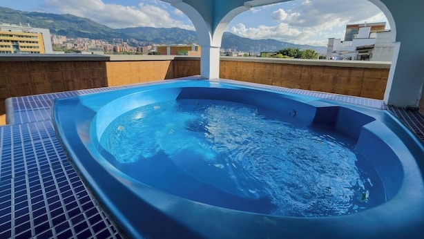 A hot tub with a cityscape view, surrounded by a tiled deck and a wooden wall. - Hotel Alcaravan (Medellin)