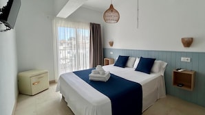 A neatly made bed with a blue and white bedspread, a bedside table with a lamp, and a small wooden nightstand with a remote control. - Ca sa Madona (Calvià)