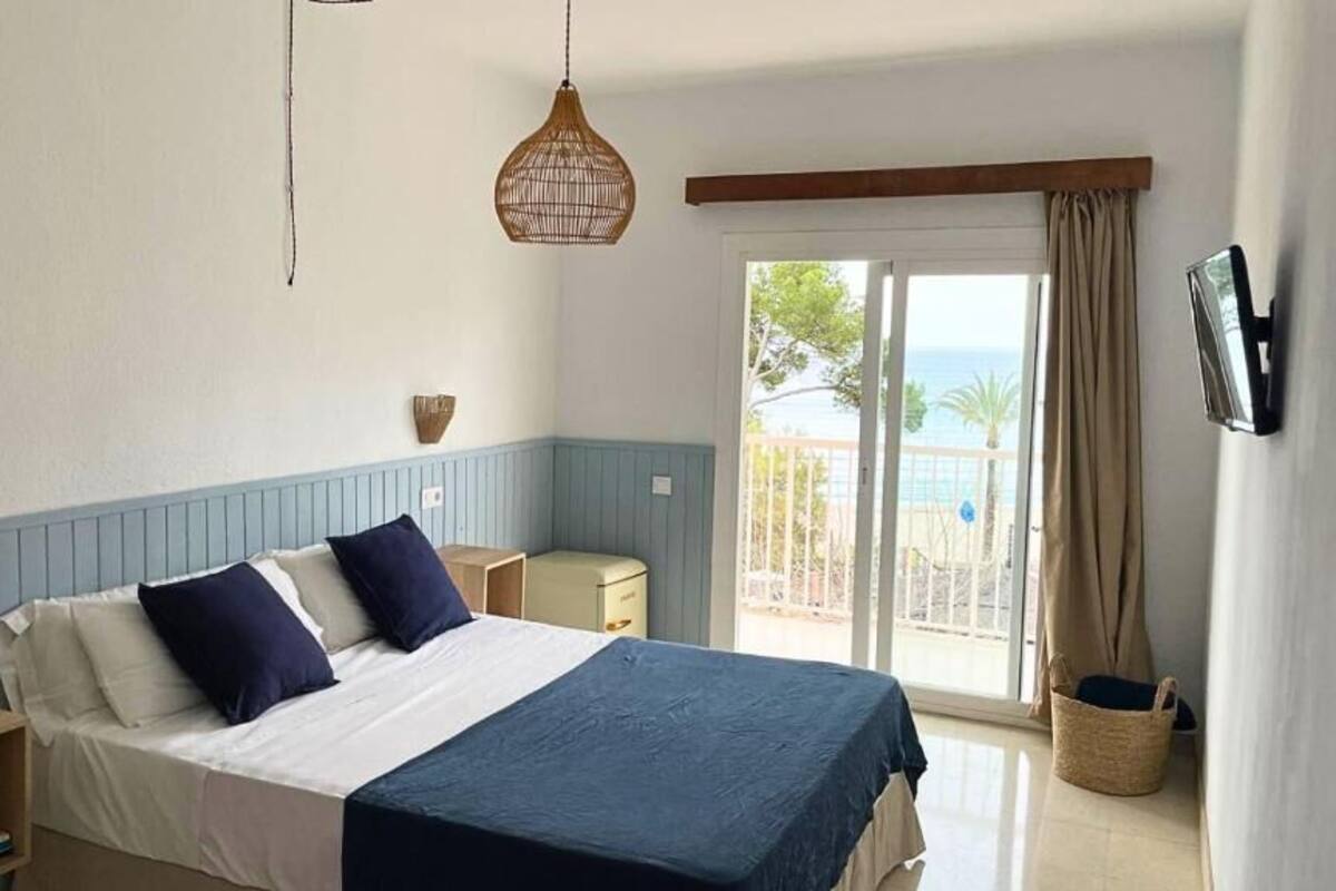 A bedroom with a bed, bedside tables, a TV, and a view of the outdoors.