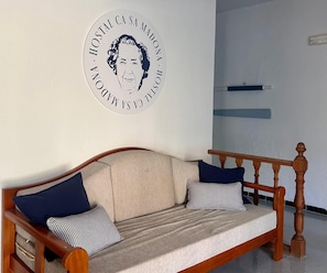 A wooden sofa with a beige cushion and two pillows, a wall with a circular sign, and a wooden headboard. - Ca sa Madona (Calvià)