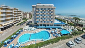 A hotel with a swimming pool, multiple balconies, and a view of the sea. - Concord (Ravenna)