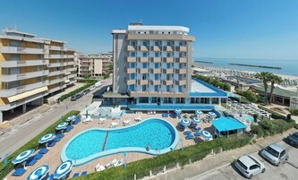 Un hotel con piscina, varios balcones y vista al mar.