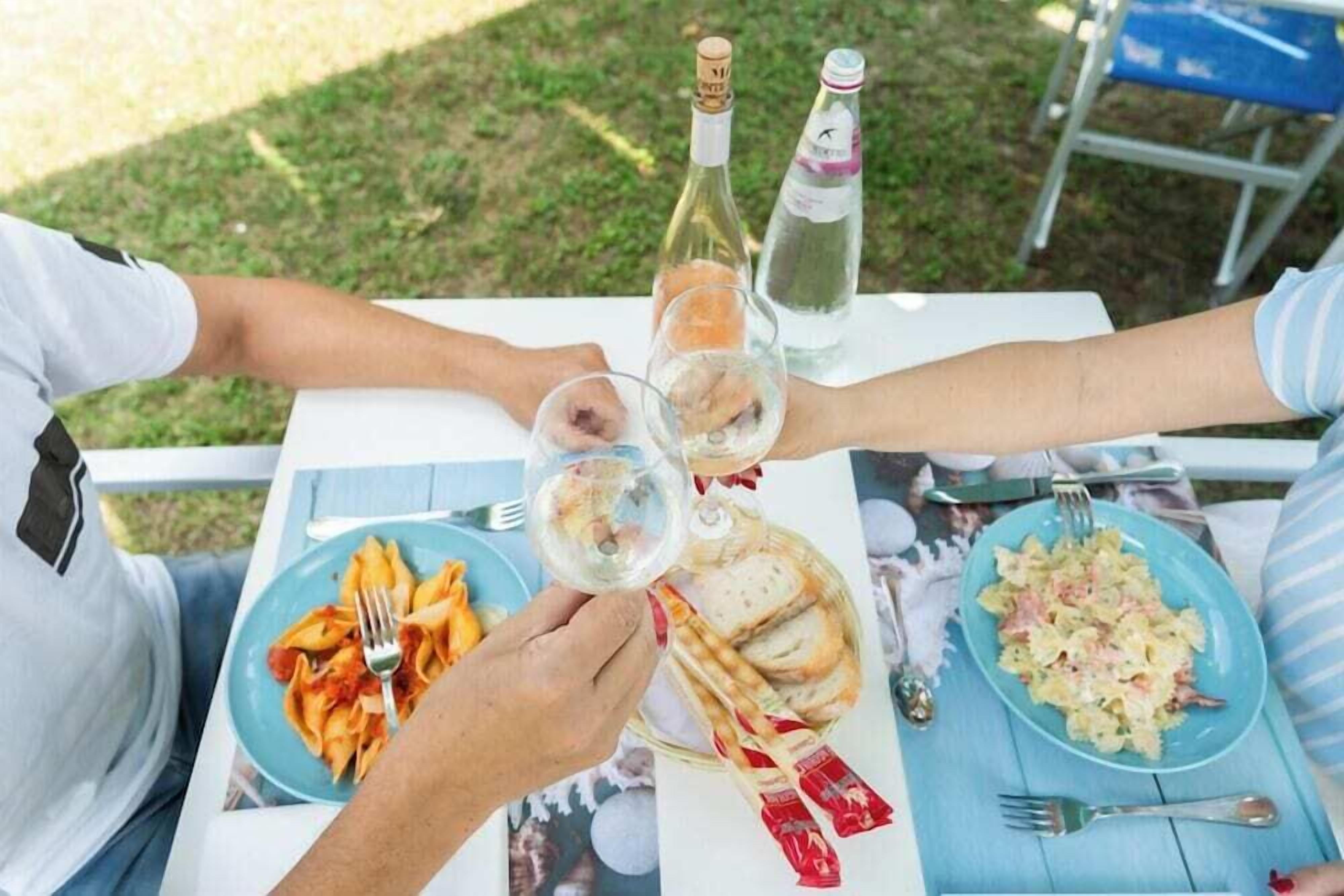 A table with plates of pasta, a bottle of wine, and a glass of water.