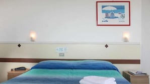 A hotel room with a bed, a nightstand, a wall-mounted light, and a framed picture. - Concord (Ravenna)