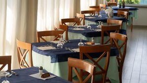A restaurant with multiple tables, each set with cutlery, glasses, and a menu. - Concord (Ravenna)