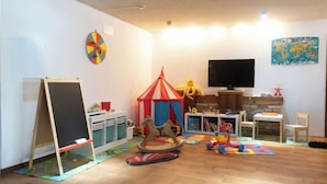 A child-friendly room with a chalkboard, a play tent, a carousel, and a television. - Concord (Ravenna)
