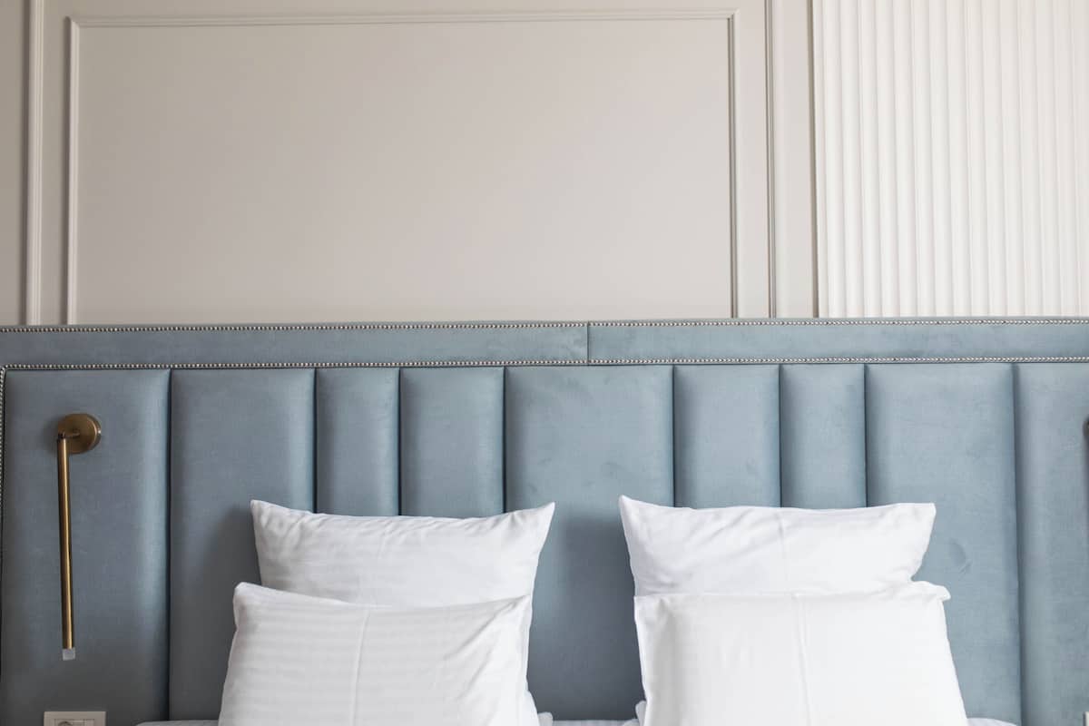 A bed with a headboard, two white pillows, and a bedside table with a lamp.
