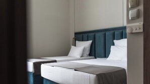 Hotellihuone, jossa on kaksi sänkyä, ja jokaisessa sängyssä on pääty ja valkoiset vuodevaatteet.