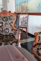 Una habitación con un sofá estampado, un cuadro en un caballete y un piso de baldosas.