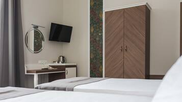 Una habitación de hotel con una cama, un escritorio con teléfono, un televisor de pantalla plana y un armario.