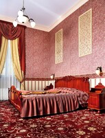 Una habitación con una cama grande, una mesita de noche de madera, un escritorio y un candelabro.