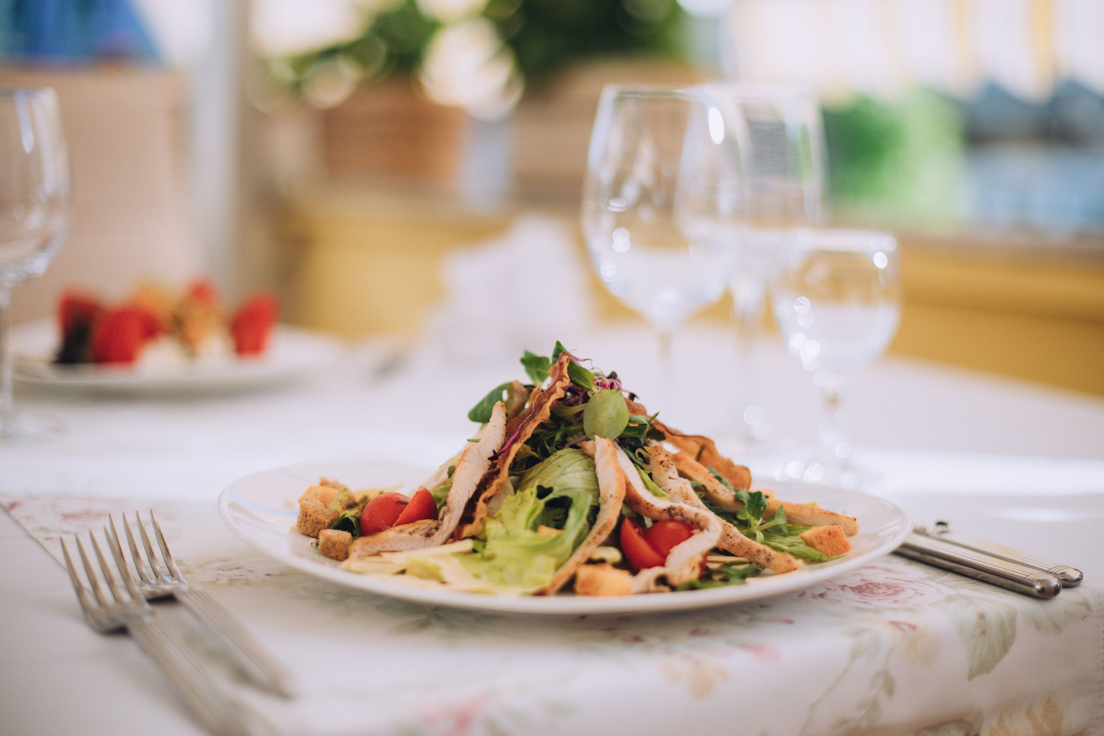 A dining table with a plate of food, a fork, and a wine glass.