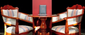 A wooden table with a red pillar and two upholstered chairs with striped patterns. - Anna Palace (Ruse)