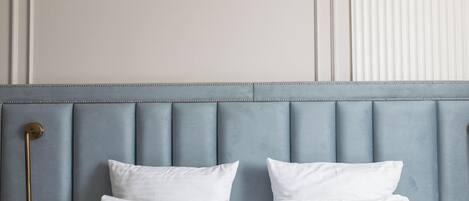 A bed with a headboard, two white pillows, and a bedside table with a lamp.