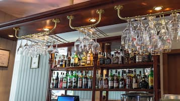 A bar area with a wine rack, shelves of liquor bottles, and a computer monitor.