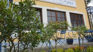 Ein Gebäude mit einem Schild, auf dem "Landgasthof Alblick" steht, und einem blauen Außenbereich mit Stühlen und Tischen.