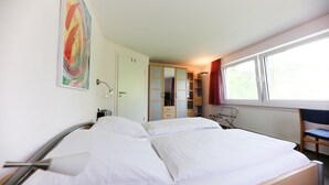 Ein Hotelzimmer mit Bett, Kleiderschrank, Schreibtisch und Fenster.