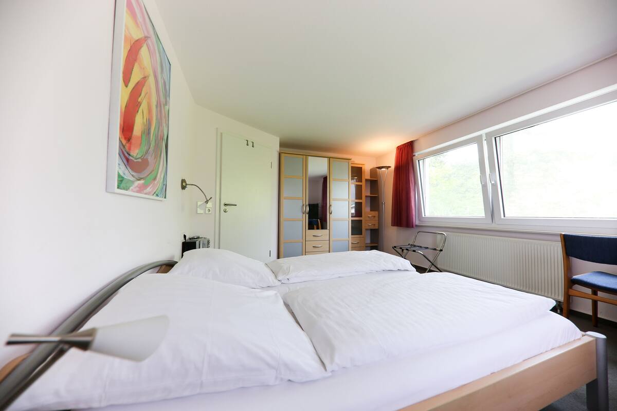 Een hotelkamer met een bed, een kledingkast, een bureau en een raam.