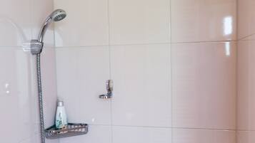 Baño con ducha, cabezal de ducha manual y dispensador de jabón en un estante.
