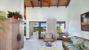 A spacious living area with a wooden cabinet, wicker furniture, and a view of the outdoors.