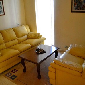 Un salon avec un canapé jaune, un fauteuil assorti et une table basse.