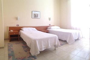 Two single beds with white linens, a small bedside table with a phone, and a framed picture on the wall. - Akropoli Hotel (Golem)