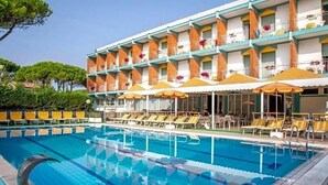 Un hotel con piscina, varios balcones y sillas de sol.
