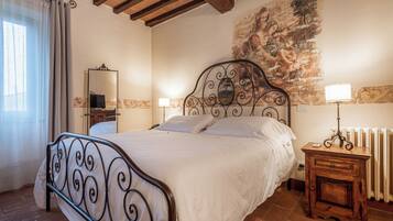 Quarto com cama, mesa de cabeceira, espelho e radiador.