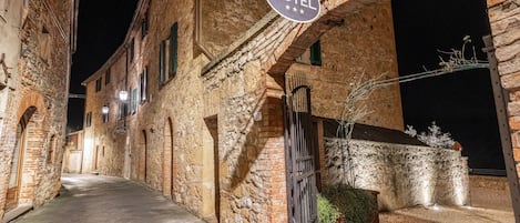 Una calle estrecha con un letrero de hotel, edificios de piedra y una entrada con reja.