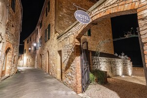 Una calle estrecha con un letrero de hotel, edificios de piedra y una entrada con reja.