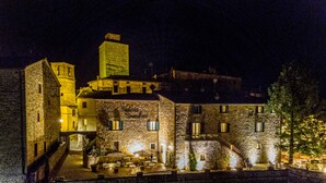 A historic stone building with multiple windows and a central staircase, surrounded by a low stone wall. - Palazzo Brandano (Trequanda)