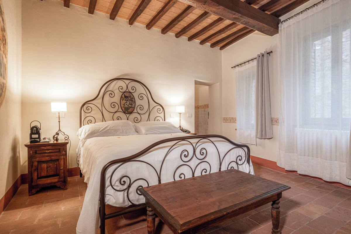 A bedroom with a wooden bed frame, bedside tables, and a nightstand.