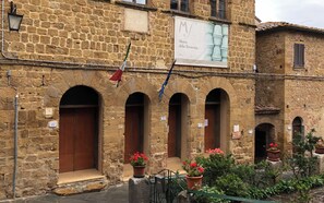 A stone building with arched doorways, a flag, and a banner for Museo della Terracotta.
