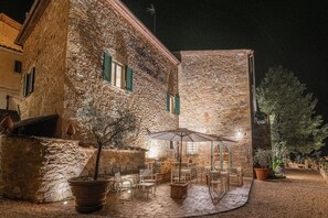 A stone building with a courtyard, outdoor seating, and a large umbrella.