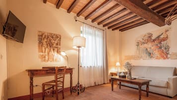 Uma sala de estar aconchegante com teto de madeira, um sofá, uma mesa de centro, uma escrivaninha com cadeira e uma luminária.