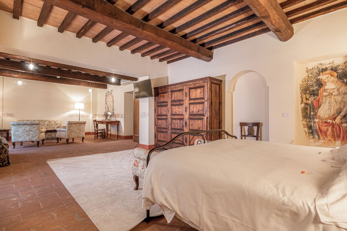 A bedroom with a large bed, wooden wardrobe, and a painting on the wall.