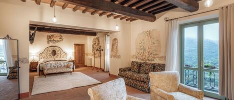 Una habitación amplia con una cama grande, dos sillones, un sofá y vistas al exterior a través de un ventanal.