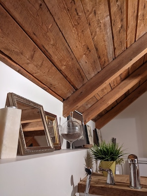 Experience the warmth of a traditional space with exposed beams, a potted plant, and a functional area for food preparation.