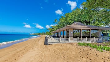 A beach with a covered pavilion, sandy beach, and ocean view.