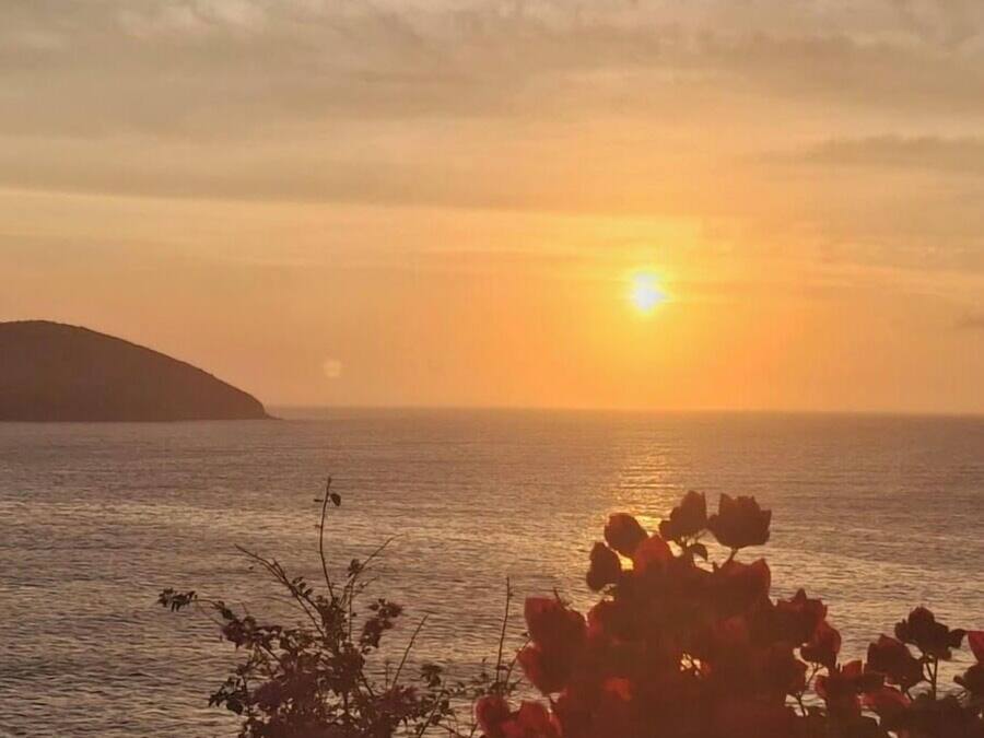 Un atardecer sobre una masa de agua con una tierra a lo lejos.