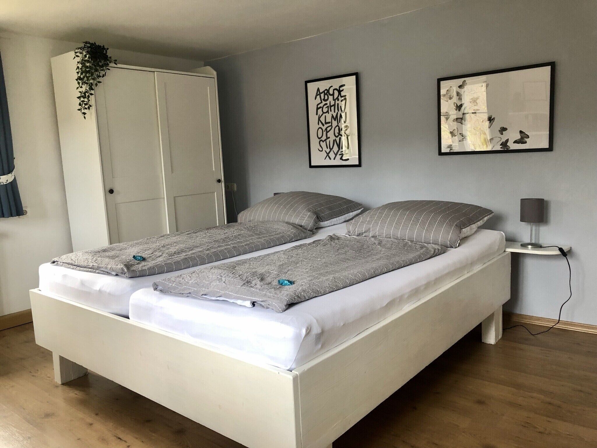 Une chambre à coucher comprenant un lit, une armoire, une table de chevet et deux œuvres d’art murales.
