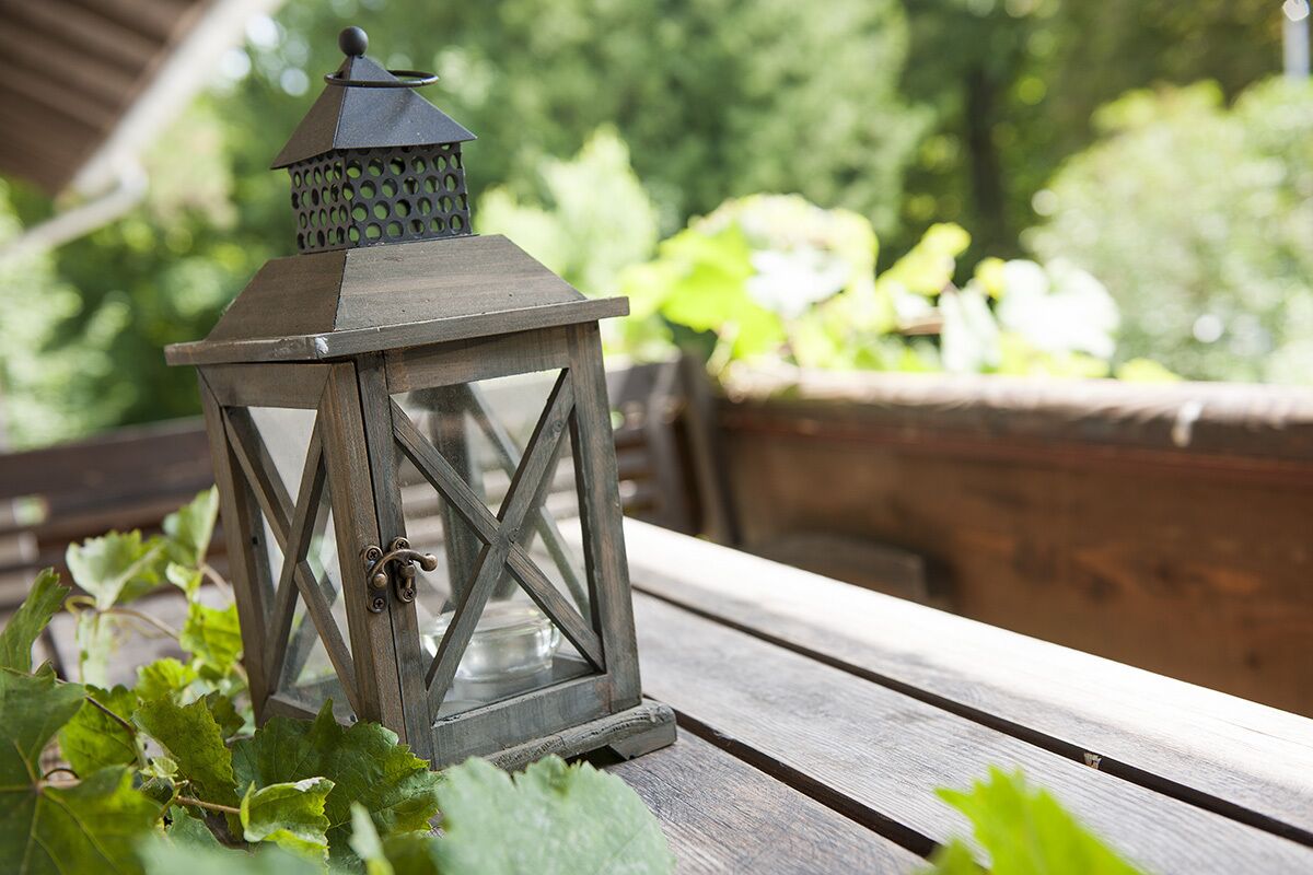 Un farol sobre un banco de madera, con follaje al fondo.