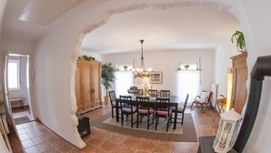 A dining area with a round table, chairs, and a chandelier. There is a fireplace and a plant in the room. - Exclusive vacation in the historic building in Chiemgau   (Traunstein)