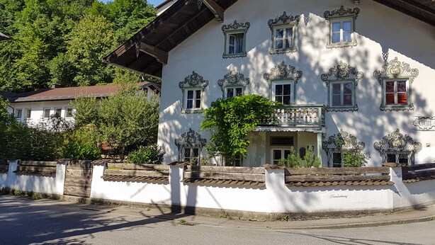 A traditional building with ornate window frames, a balcony, and a white facade. - Exclusive vacation in the historic building in Chiemgau   (Traunstein)