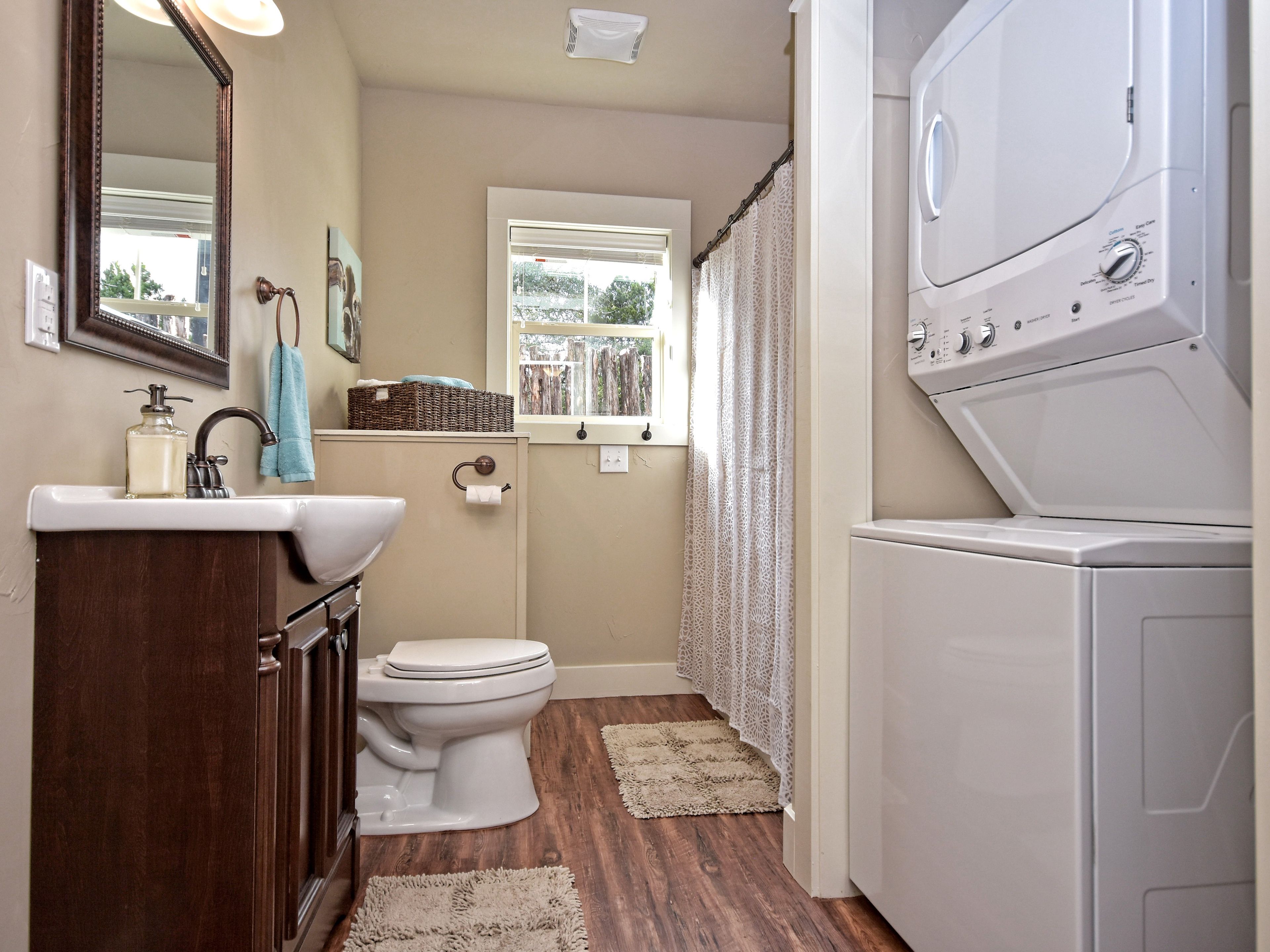 A compact bathroom with a toilet, sink, and a stacked washer and dryer.