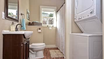 A compact bathroom with a toilet, sink, and a stacked washer and dryer.