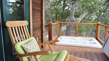 A wooden deck with a wooden chair and a hot tub.