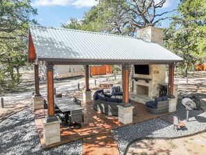 A covered outdoor seating area with stone pillars, a built-in grill, and a stone fireplace. - Morning Dove I Romantic, Minutes from The Square! (Wimberley)