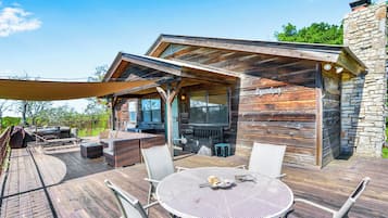 A wooden cabin with a covered patio, outdoor seating, and a stone wall.